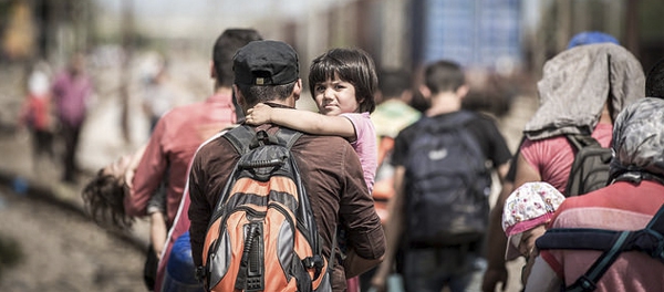 A Syrian father carries his daughter to register with the Macedonian authorities before proceeding north towards Serbia. Macedonia last week announced a state of emergency and deployed riot police at the border last week. Photo © Stephen Ryan / IFRC